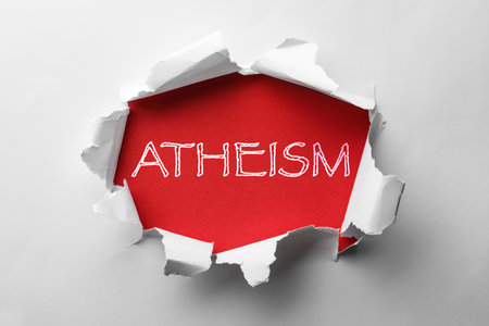 Word Atheism on red background, view through hole in white paperの写真素材