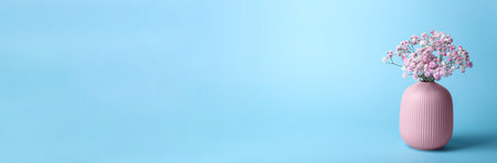 Beautiful gypsophila flowers in pink vase on light blue background, space for text. Banner designの写真素材
