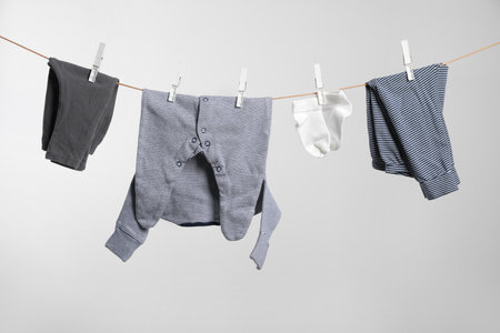Cute baby clothes drying on washing line against white backgroundの写真素材