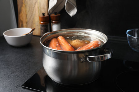 Boiling carrots and potatoes in pot on electric stove. Cooking vinaigrette salad