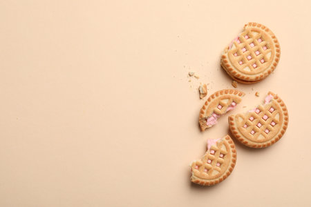 Tasty sandwich cookies with cream on beige background, flat lay. Space for textの写真素材