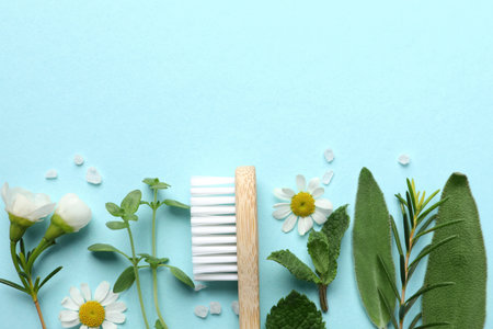 Bamboo toothbrush, beautiful flowers, sea salt and herbs on turquoise background, flat lay. Space for textの写真素材
