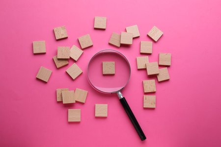 Magnifying glass and pieces of wood on pink background, flat layの写真素材