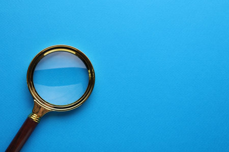 Magnifying glass on light blue background, top view. Space for textの写真素材