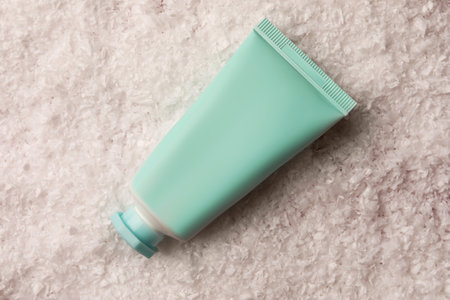 Winter skin care. Hand cream on white artificial snow, top viewの写真素材