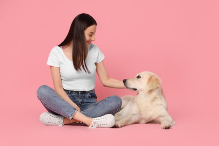 Happy woman with cute Labrador Retriever dog on pink background. Adorable petの写真素材