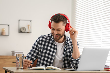 Man in headphones studying on laptop at home. Online translation course