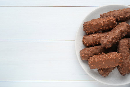 Tasty sweet chocolate bars on white wooden table, top view. Space for text