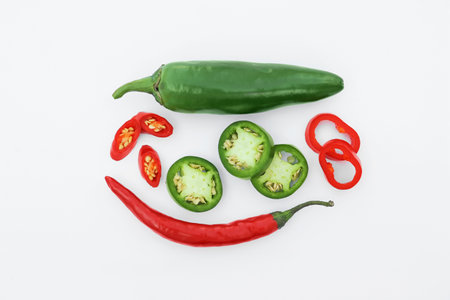 Whole and cut hot chili peppers on white background, flat lay