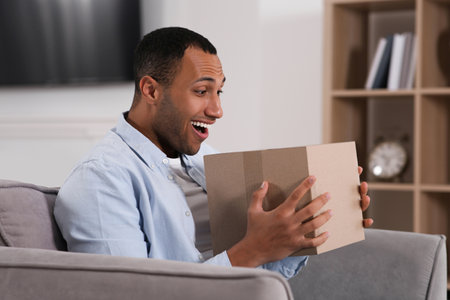 Emotional young man with parcel at home. Internet shoppingの写真素材