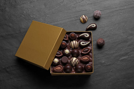 Open box of delicious chocolate candies on black table, flat layの写真素材