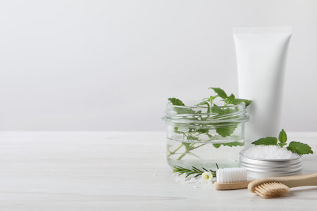 Toothbrushes, dental products and herbs on white wooden table. Space for textの写真素材