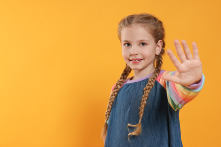 Cheerful girl giving high five on orange background, space for textの写真素材
