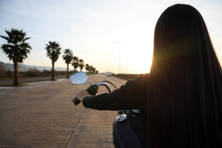 Woman riding motorcycle at sunset, back view. Space for textの写真素材