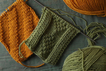 Soft yarns, knitting and metal needles on light blue wooden table, flat lay