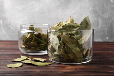 Bay leaves in glass jars on wooden tableの写真素材
