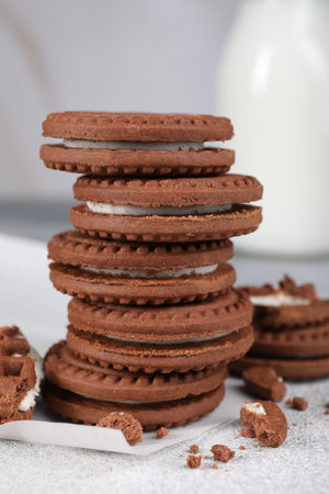 Tasty chocolate sandwich cookies with cream on light gray table, closeup