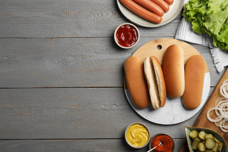 Different tasty ingredients for hot dog on light gray wooden table, flat lay. Space for textの写真素材