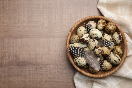 Speckled quail eggs and feathers on wooden table, top view. Space for textの写真素材