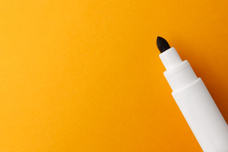 Black marker on orange background, top view. Space for text