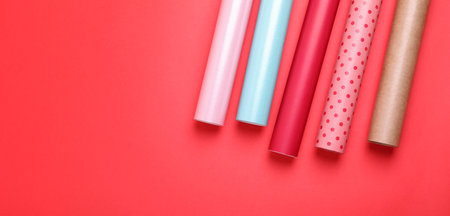 Rolls of colorful wrapping papers on red background, flat lay. Space for textの写真素材
