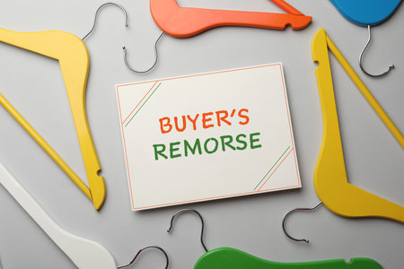 Card with text Buyer's Remorse and different colorful hangers on light gray background, flat layの写真素材