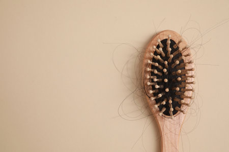 Wooden brush with lost hair on beige background, top view. Space for textの写真素材