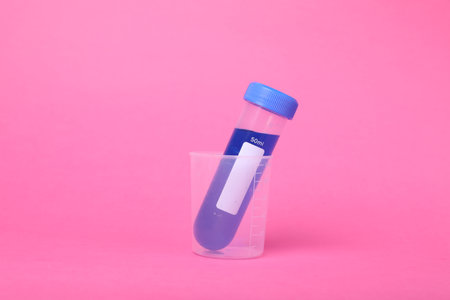 Beaker with test tube and liquid on bright pink background. Kids chemical experiment setの写真素材