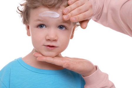 Mother applying ointment onto her son`s forehead on white background, closeupの写真素材