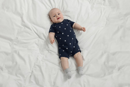 Cute baby lying on white bed, above view. Space for textの写真素材