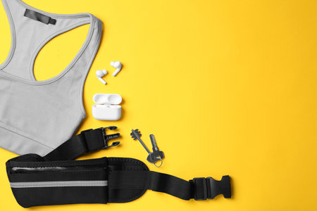 Flat lay composition with stylish black waist bag on yellow background, space for text