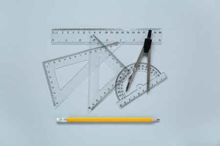 Different rulers with measuring length markings and compass on light gray background, flat lay
