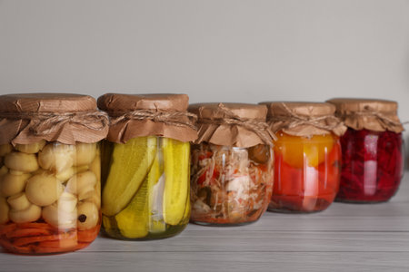 Many jars with preserved vegetables on white wooden tableの写真素材