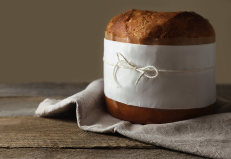 Delicious Panettone cake wrapped in parchment paper on wooden table, space for text. Traditional Italian pastryの写真素材