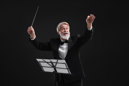 Professional conductor with baton and note stand on black backgroundの写真素材