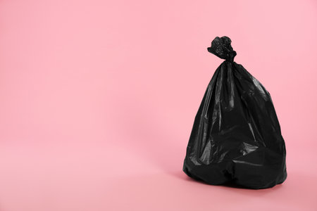 Trash bag full of garbage on pink background. Space for textの写真素材