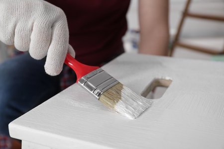 Man using brush to paint bekvam with white dye indoors, closeupの写真素材