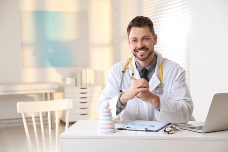 Pediatrician with stethoscope at table in clinicの写真素材