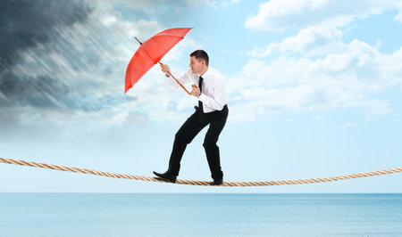Risks and challenges of entrepreneurship. Businessman with umbrella protecting from coming rainstorm...
