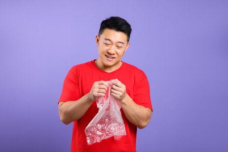 Happy asian man with pooping wrap on purple background