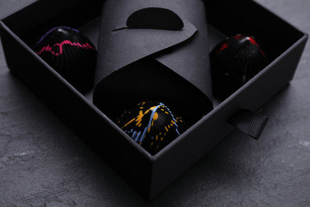 Box of tasty chocolate candies on black table, closeup
