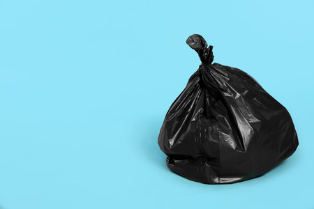 Trash bag full of garbage on light blue background. Space for textの写真素材