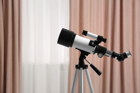 Tripod with modern telescope in stylish room, closeup. Space for text