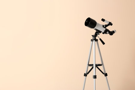 Tripod with modern telescope on beige background. Space for textの写真素材