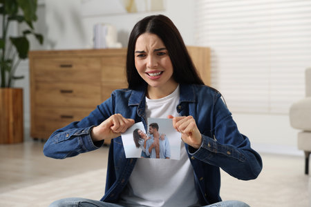 Upset woman ripping photo at home. Divorce conceptの写真素材