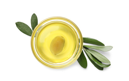 Olive oil in bowl and leaves on white background, top view. Healthy cookingの写真素材