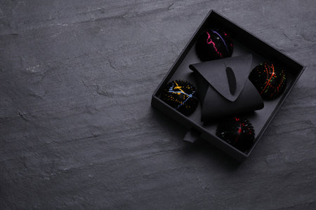 Box of tasty chocolate candies on black table, top view. Space for text