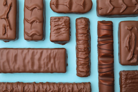 Different tasty chocolate bars on light blue background, flat lay