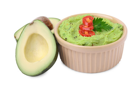 Bowl of delicious guacamole with chili pepper and fresh avocado isolated on whiteの写真素材