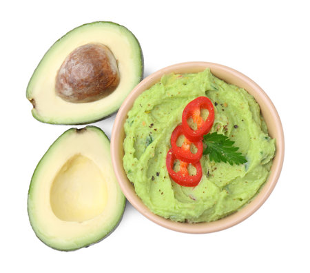 Bowl of delicious guacamole with chili pepper and fresh avocado isolated on white, top viewの写真素材